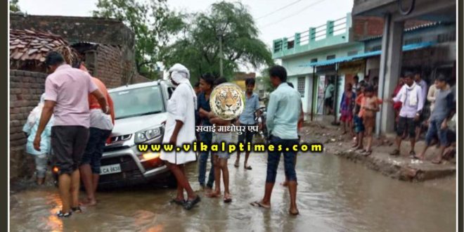Rain water on road, car stuck in drain